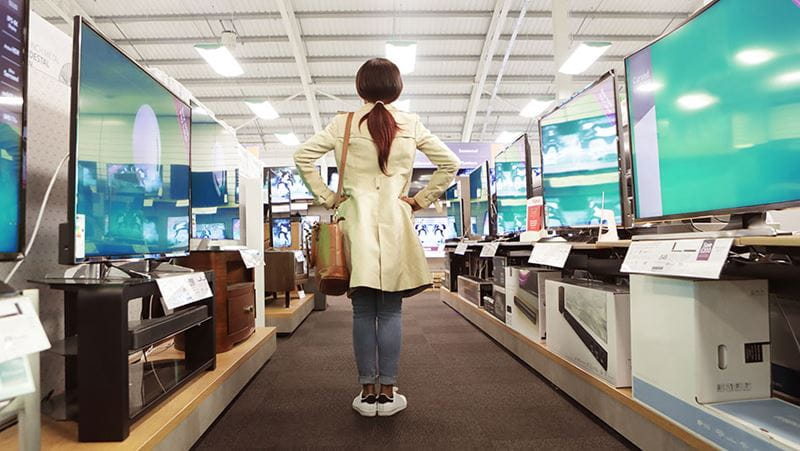 Woman in store looking at different television options